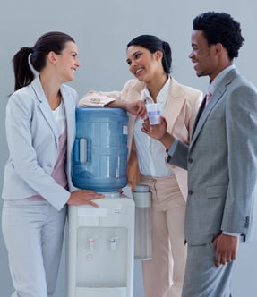 Business people speaking next to a water cooler in office Business people speaking next to a water cooler in office