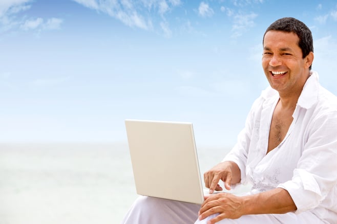 beach man happy and smiling on a laptop computer